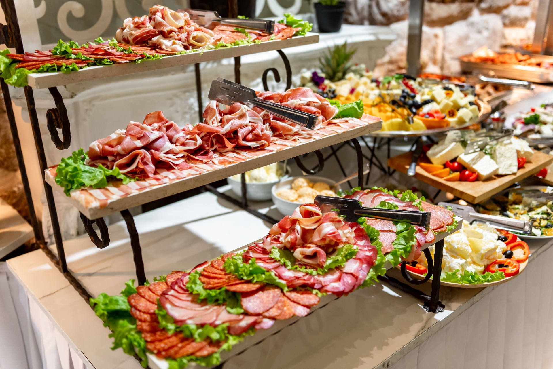 Delightful assortment of fresh deli meats and greens on a beautifully arranged buffet table at a bustling banquet venue
